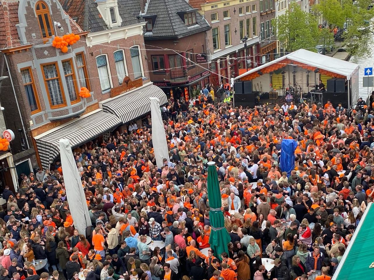 De Platte Stenen Brug in Alkmaar vol mensen tijdens Koningsdag, met de gracht en de historische gevels